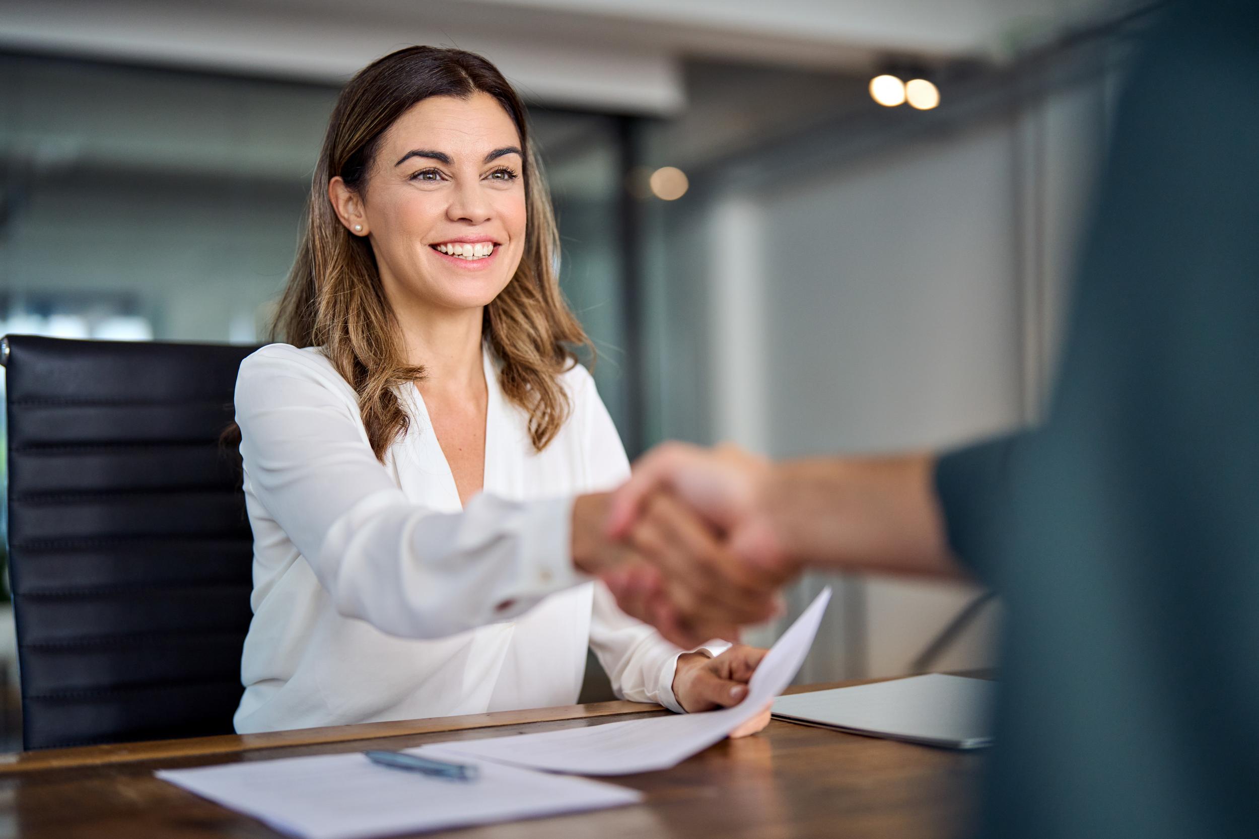 smiling woman shaking the hand across from her at a table