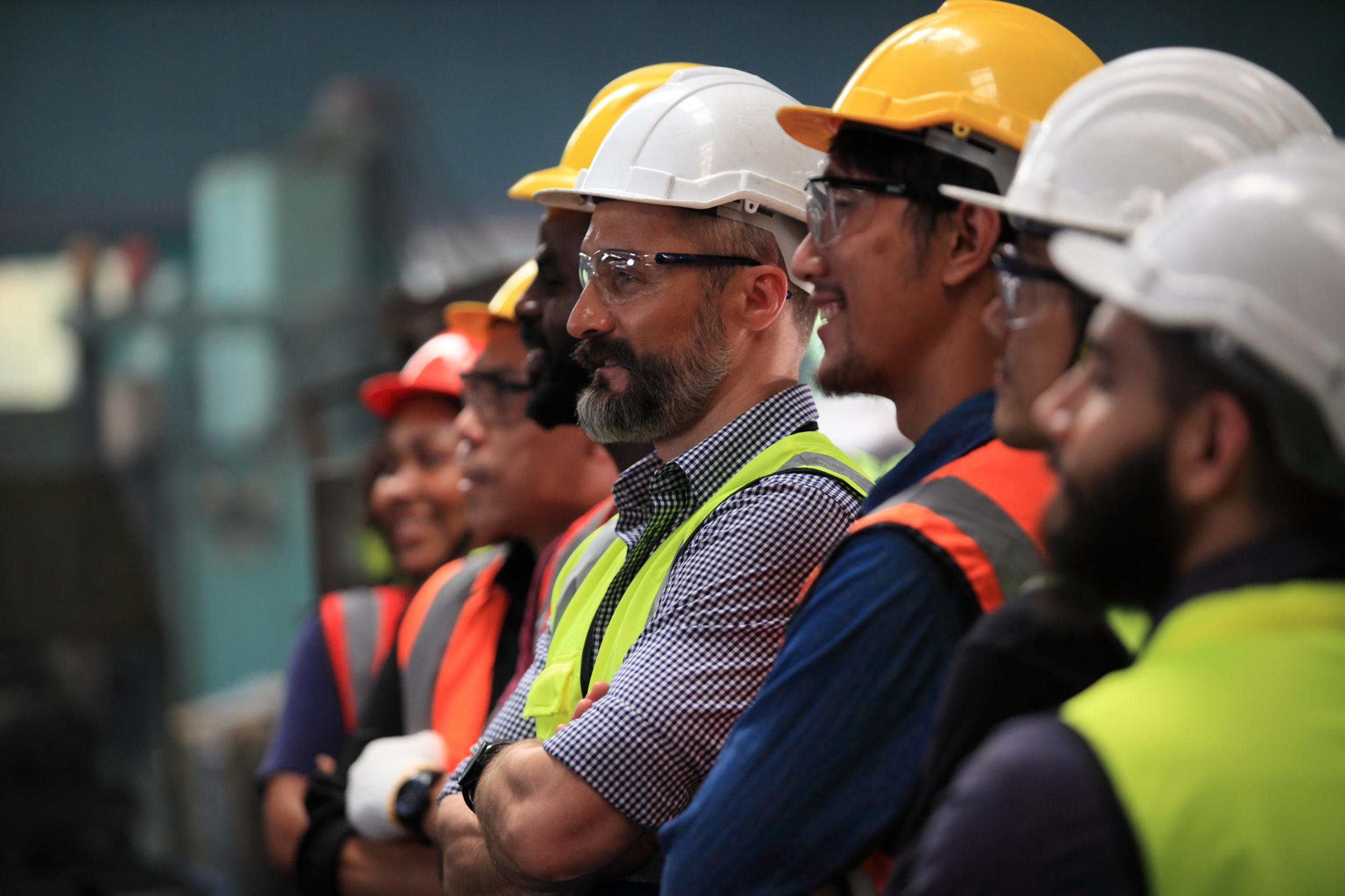 A line of men in hard-hats and orange vests