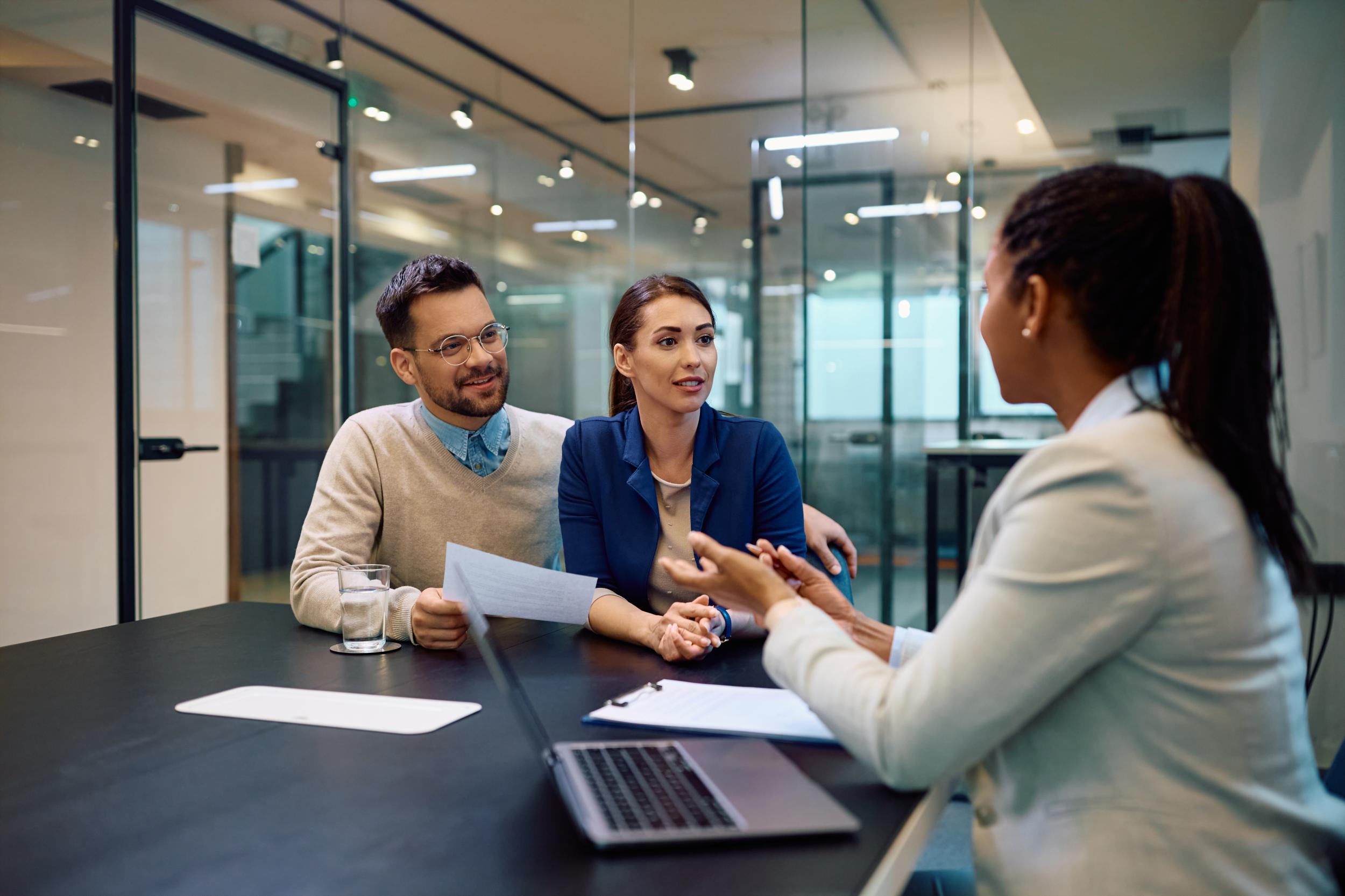 woman discussing something with a married couple sitting at a conference table